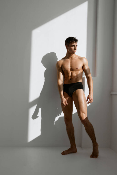 man with pumped up muscular body black underpants basing light background - Fotoğraf, Görsel