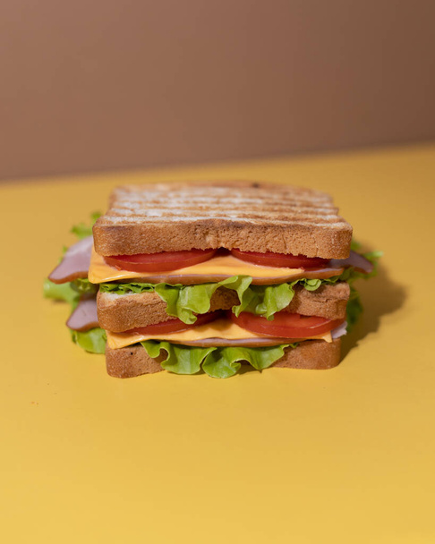 Традиционный сэндвич из ломтиков поджаренного хлеба, сыра, ветчины, свежего салата. Празднование Национального дня сэндвича. - Фото, изображение