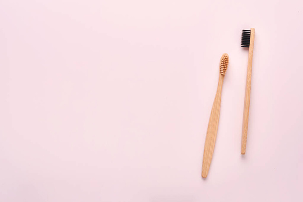 Teeth hygiene and oral dental care products on pink color background with copy space. Eco-friendly bamboo toothbrushes and cotton flowers. Flat lay, top view composition, mockup. Morning concept. - Φωτογραφία, εικόνα