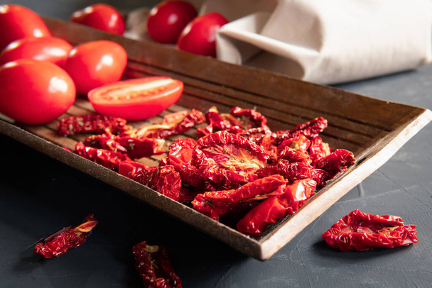 Dried tomatoes are on a dark background in the kitchen. - Foto, imagen