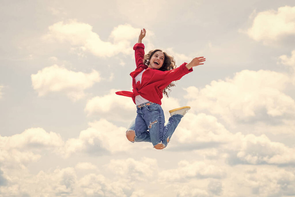 Happy kid wear red jacket. Lifestyle and People Concept. kid spring and fall fashion. full of energy. childhood happiness. teen girl jumping high in the sky. having a party fun - Photo, Image