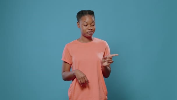 Afričanky americká žena ukazuje prsty bokem ve studiu - Záběry, video