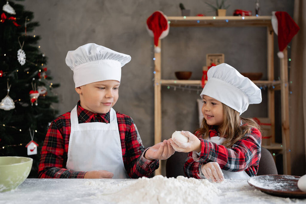 Happy children in the kitchen make dough for Christmas cookies, a family in the kitchen prepares gingerbread cookies, little cooks break an egg. Christmas food concept - Zdjęcie, obraz