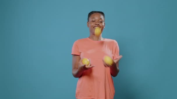 Mujer positiva haciendo malabares con limones frescos y sonriendo - Imágenes, Vídeo