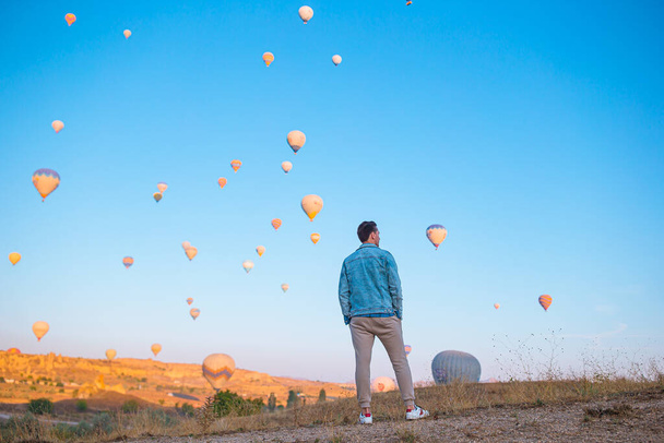 Glücklicher Mann bei Sonnenaufgang und Heißluftballons in Kappadokien, Türkei - Foto, Bild