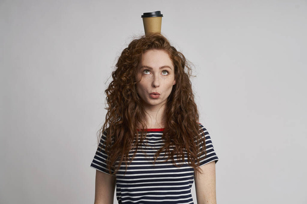 Lustiges Mädchen mit Tasse Kaffee auf dem Kopf                                - Foto, Bild