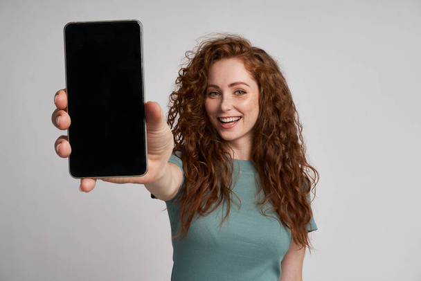 Redhead showing screen of mobile phone                               - Zdjęcie, obraz