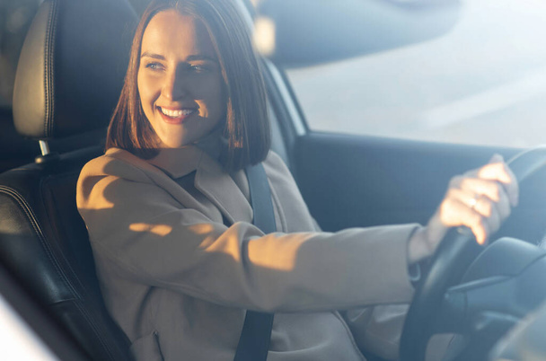 Cheeeful young woman is driving a car - Photo, Image