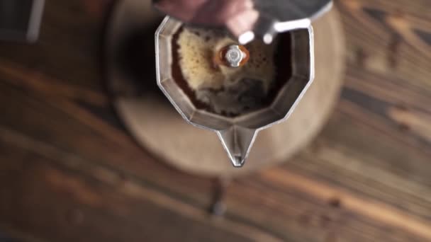 Bereiding van heerlijke zwarte koffie Italiaanse moka. Geyser koffiezetapparaat op een houten tafel op een donkere achtergrond. - Video