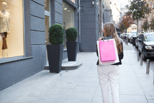 Žena procházející kolem módní obchod ve městě, při pohledu na maloobchodní displej, kopírovací prostor - Fotografie, Obrázek