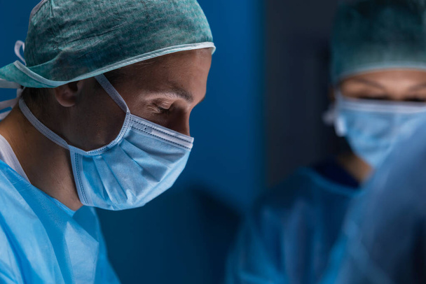 Multiracial team of professional medical surgeons performs the surgical operation in a modern hospital. Doctors are working to save the patient. Medicine, health, cardiology and transplantation. - Fotografie, Obrázek