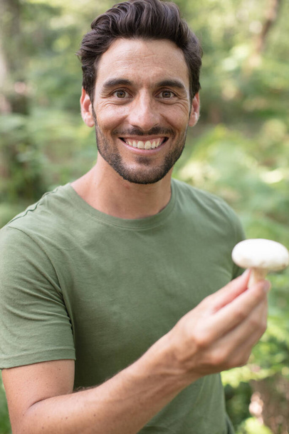 unrecognizable young man picking mushrooms in autumn forest - Photo, Image