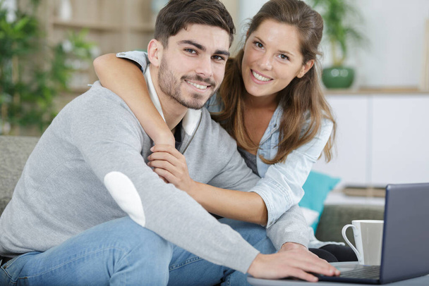embracing couple using laptop at home - 写真・画像