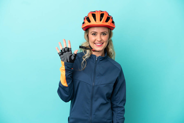 Young cyclist woman isolated on blue background saluting with hand with happy expression - Fotografie, Obrázek