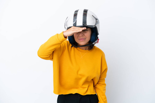 Жінка з мотоциклетним шоломом дивиться далеко з рукою, щоб щось виглядати
 - Фото, зображення