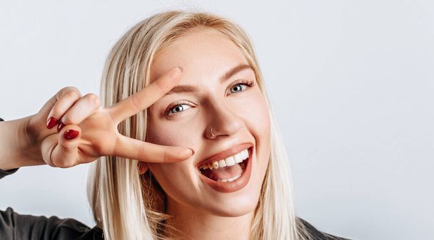 Hey smile you. Portrait of cheeky and cute glamor blond woman combed hair and jacket winking happily showing peace victory gesture as fooling around, being optimistic - Foto, Imagem