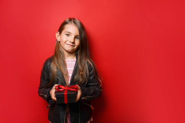 Child girl holding black gift box on red background with copy space. Black Friday concept - Fotografie, Obrázek