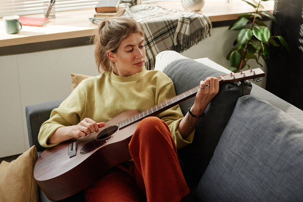 жінка вчиться грати на гітарі вдома
 - Фото, зображення