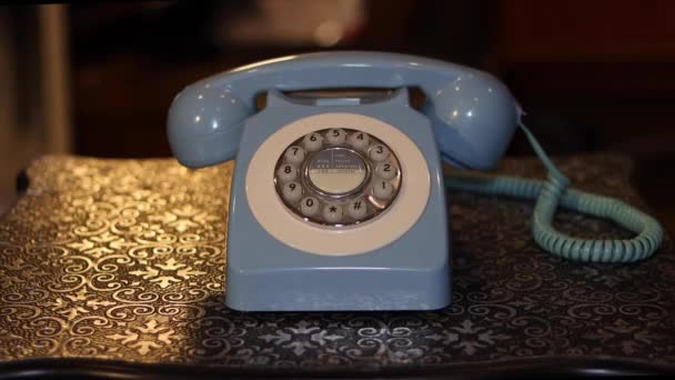 Un viejo teléfono sobre un fondo de mesa de metal con un macho cogiendo el teléfono y colgándolo. - Metraje, vídeo