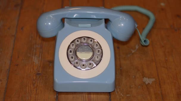 Un viejo teléfono sobre un fondo de madera con un macho cogiendo el teléfono y colgándolo. - Metraje, vídeo