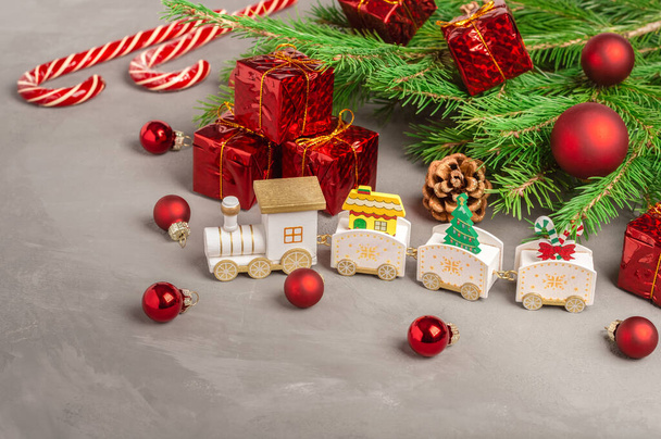 Χριστουγεννιάτικο τρένο, κουτιά με δώρα, στολίδια και καραμέλες κάτω από τα κλαδιά ενός χριστουγεννιάτικου δέντρου. Αντιγραφή χώρου. - Φωτογραφία, εικόνα