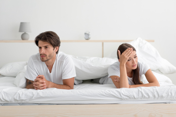 Offended angry young caucasian couple lying on bed ignoring partner in bedroom - Valokuva, kuva