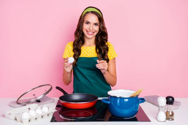 Photo of cute sweet young lady dressed green apron preparing tasty scrambled eggs isolated pink color background. - Zdjęcie, obraz