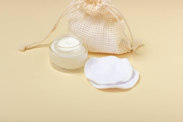 Cotton reusable makeup remover pads in a cloth bag on a beige background. The concept of ecology and conscious consumption. Reusable cotton pads - Zdjęcie, obraz