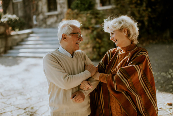 Красивая пожилая пара, обнимающаяся в осеннем парке - Фото, изображение