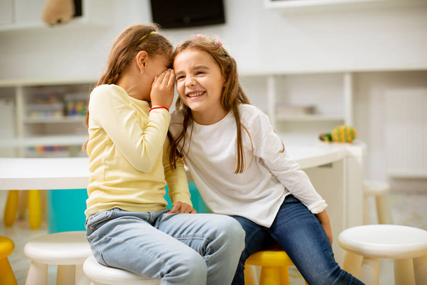 Cute little girl whispering something in an ear of her friend - Photo, Image