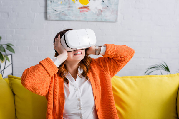 tensed woman touching head while gaming in vr headset at home - Photo, Image