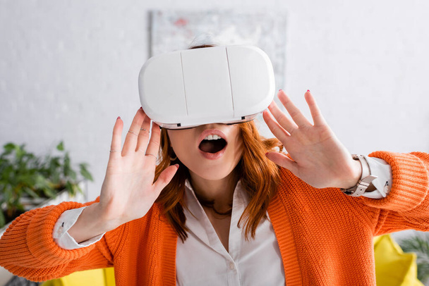 amazed woman with open mouth gesturing while gaming in vr headset at home - Foto, imagen