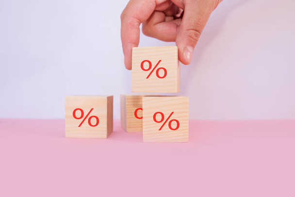 Interest rate financial and mortgage rates concept. Hand putting wood cube block increasing on top with icon percentage symbol upward direction - Photo, Image