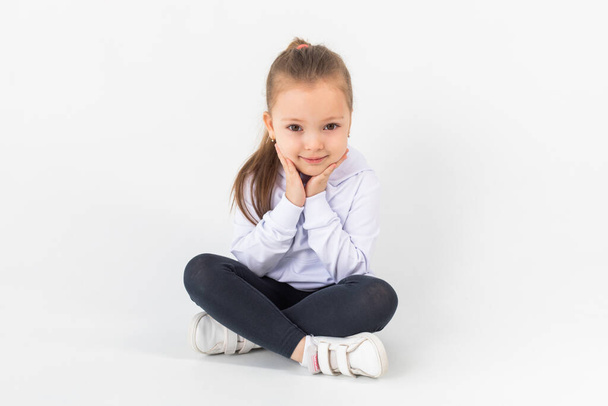 Girl in a white blank hoodie sits on a white background. Kids hoodies mockup. - Foto, imagen