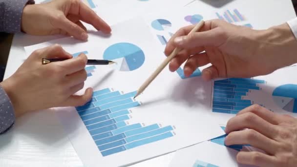 Az üzletemberek statisztikai jelentéseket elemeznek, növekedési táblázatokat az asztalon. Ötletkészítés, a cég stratégiájának megtervezése. Csapatülés - Felvétel, videó