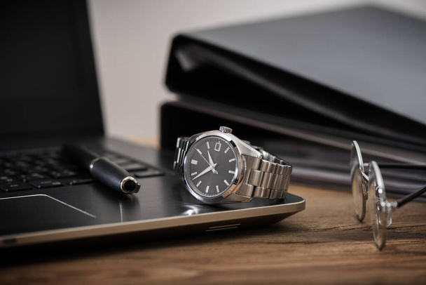 akcesoria męskie, zbliżenie na luksusowy automatyczny zegarek na rękę z czarną tarczą i bransoletką ze stali nierdzewnej. - Zdjęcie, obraz