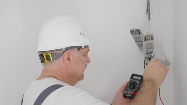 Un electricista masculino instala transformadores para la iluminación en un sistema de hogar inteligente. Verificación de la instalación Iluminación - Imágenes, Vídeo