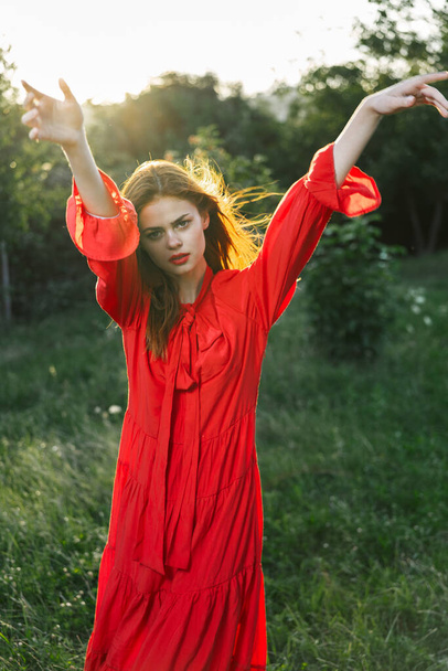 attractive woman in red dress posing in nature green grass - 写真・画像