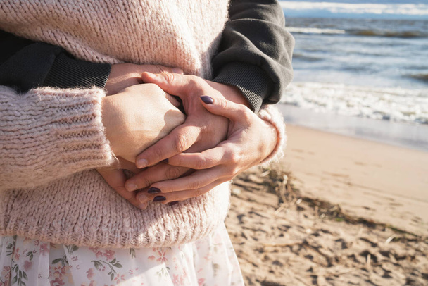 Mies pitää vaimoaan kädestä. Rakkaiden käsien lähikuva. Pari kävelee meren ohi. Todellinen rakkaus ja huolenpito ihmisten välillä. - Valokuva, kuva