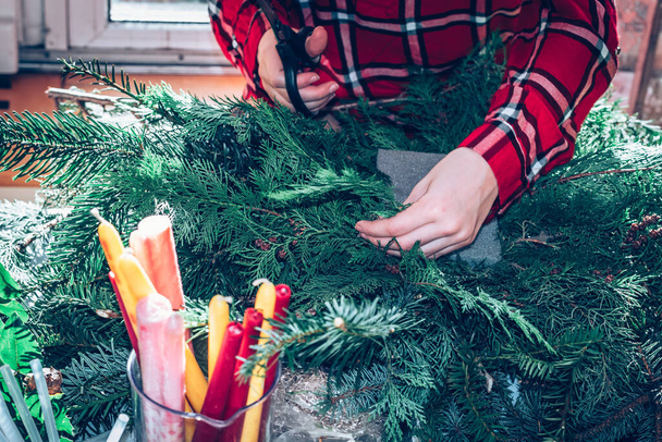 adorable rubia chica crear navidad advenimiento corona interior de pino verde planta, velas y bolas - Foto, Imagen