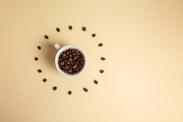 Cup of coffee seeds. Like clock, on light brown background. - Foto, imagen