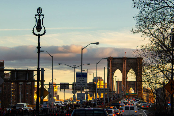 Нью - Йорк, Нью - Йорк, Нью - Йорк, США - 29 грудня 2018 р. - рух транспорту й туристів на Бруклінському мості під час зимового заходу сонця.. - Фото, зображення
