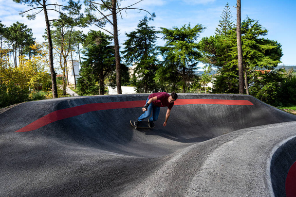 Skateboarder practice on a pump track park on a sunny day. - Photo, image