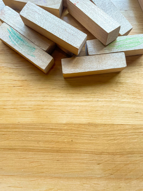 Pile of blocks from wooden blocks tower stacking game scattered on a wooden surface. Textured wooden background with copy space - Photo, Image