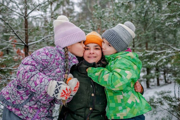 I bambini con la mamma godono della prima neve nella foresta invernale, attività stagionali attive, stile di vita - Foto, immagini
