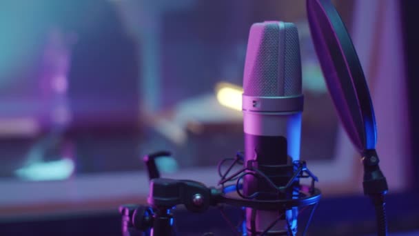 Крупный план профессионального микрофона с поп-фильтром в студии звукозаписи с фиолетовым неоновым светом - Кадры, видео