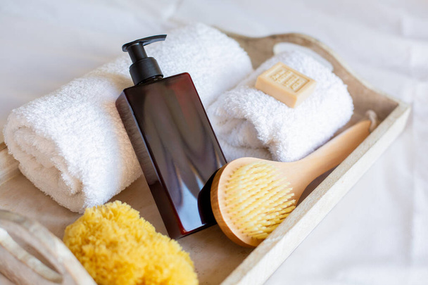 SPA set. A jar of cream with a dispenser, a wooden brush and other bath accessories are on a wooden tray. Copy space. - Photo, image