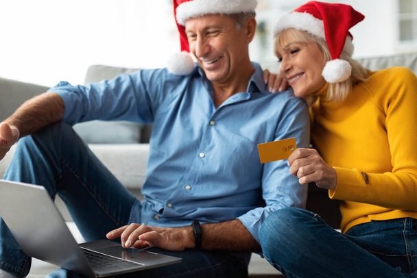 Feliz pareja de ancianos de compras en línea con sombreros de Santa en casa - Foto, imagen