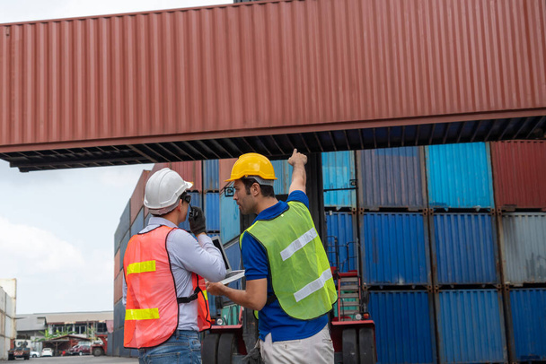 Industrial worker works with co-worker at overseas shipping container yard - Photo, Image