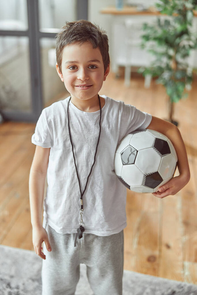 Happy boy playing football in living room - Fotó, kép